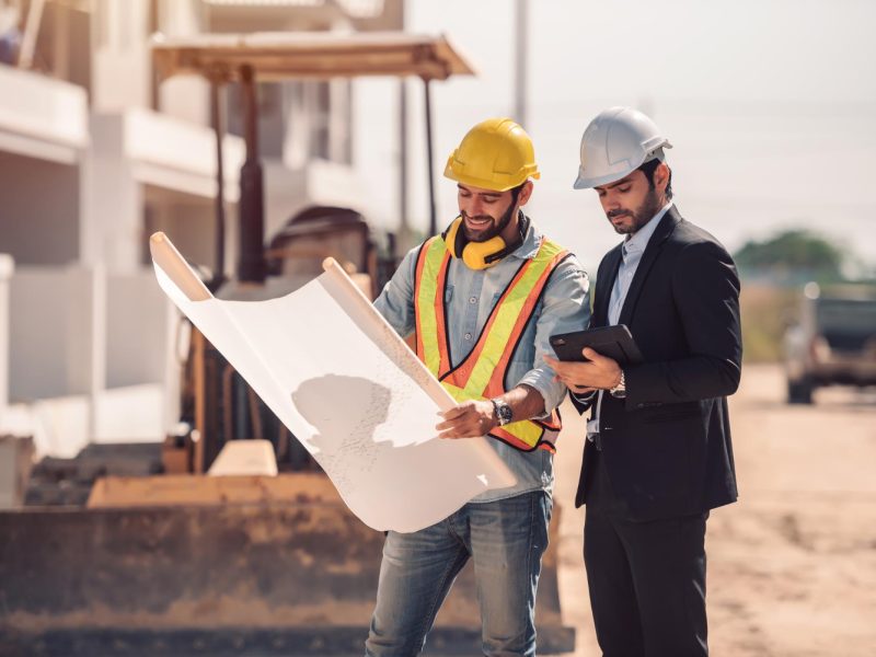 civil-engineer-construction-worker-manager-holding-digital-tablet-blueprints-talking-planing-about-construction-site-cooperation-teamwork-concept.jpg